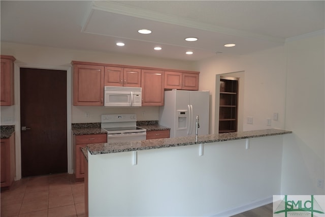 kitchen featuring a kitchen bar, white appliances, light tile floors, and dark stone counters