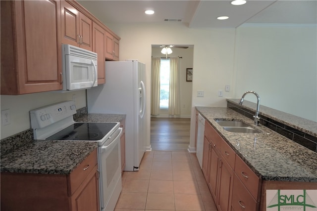 kitchen featuring white appliances, sink, light tile floors, dark stone countertops, and ceiling fan