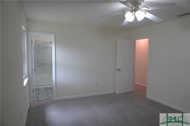 unfurnished bedroom featuring a textured ceiling, dark carpet, ceiling fan, and connected bathroom