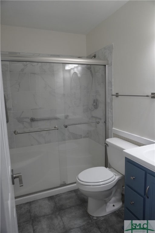 bathroom with a shower with door, vanity, tile floors, and toilet