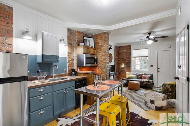 kitchen with light hardwood / wood-style floors, blue cabinets, ceiling fan, appliances with stainless steel finishes, and sink