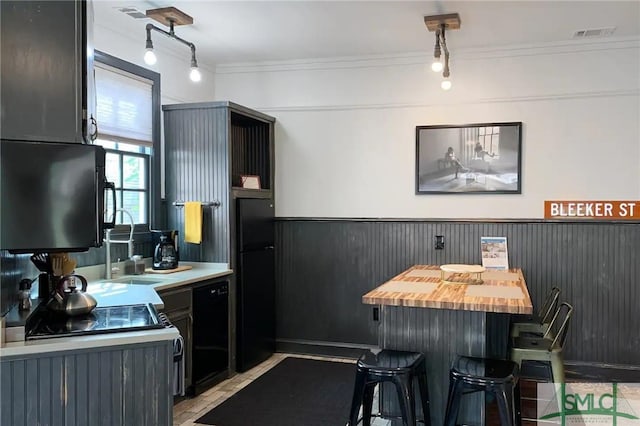 kitchen featuring black appliances, butcher block countertops, ornamental molding, and rail lighting