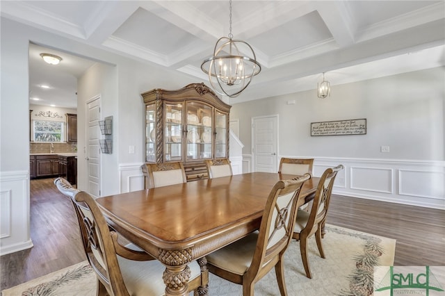 dining area with beamed ceiling, coffered ceiling, dark wood-type flooring, and a notable chandelier