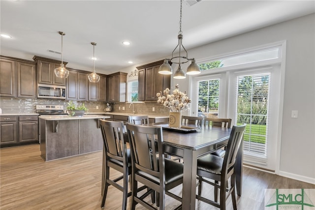 dining room featuring a notable chandelier, light hardwood / wood-style floors, and sink