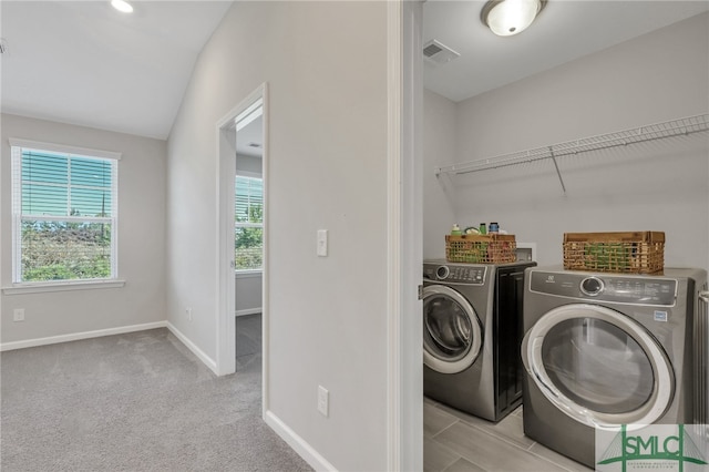 clothes washing area with light carpet and washer and dryer