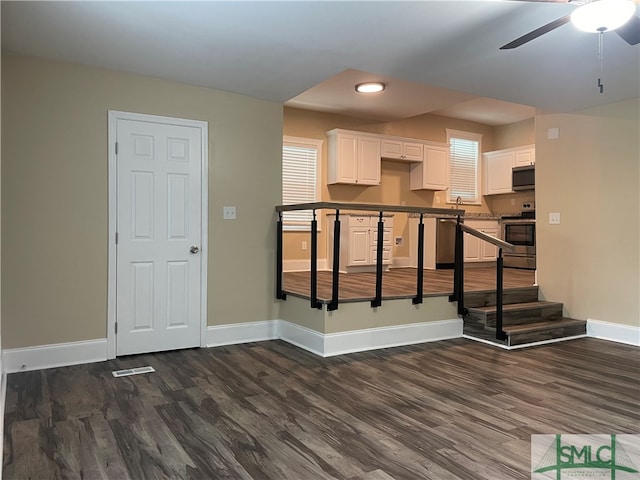 kitchen with a breakfast bar, white cabinetry, dark hardwood / wood-style floors, appliances with stainless steel finishes, and ceiling fan