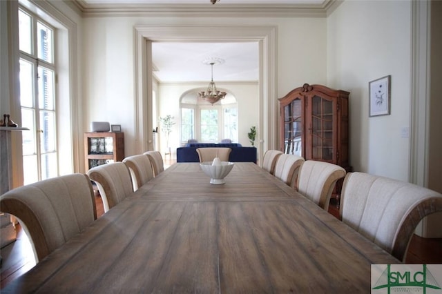 dining space featuring wood-type flooring, crown molding, and a chandelier