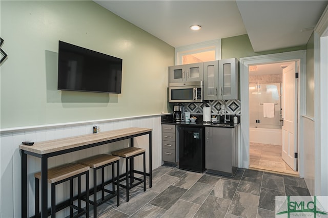 kitchen featuring backsplash, dark tile floors, dishwasher, and sink