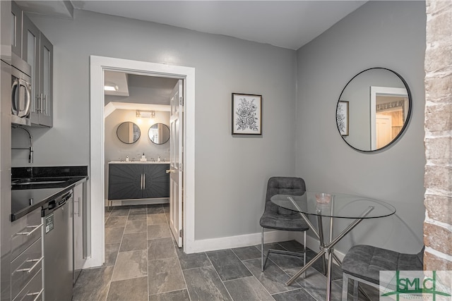 interior space with dark tile floors, appliances with stainless steel finishes, gray cabinets, and sink