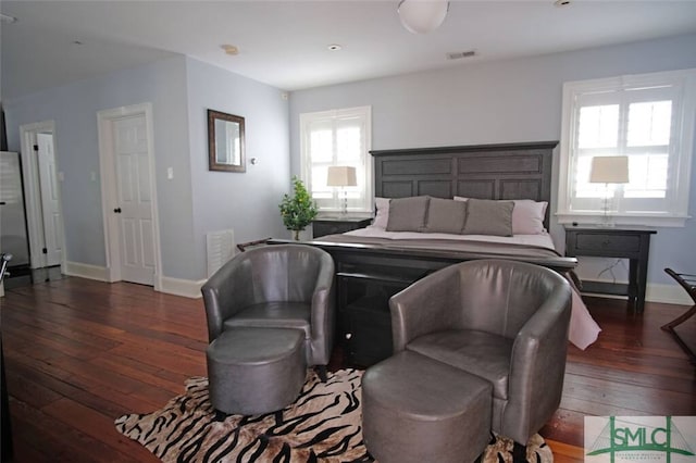 bedroom with stainless steel refrigerator, dark hardwood / wood-style flooring, and multiple windows