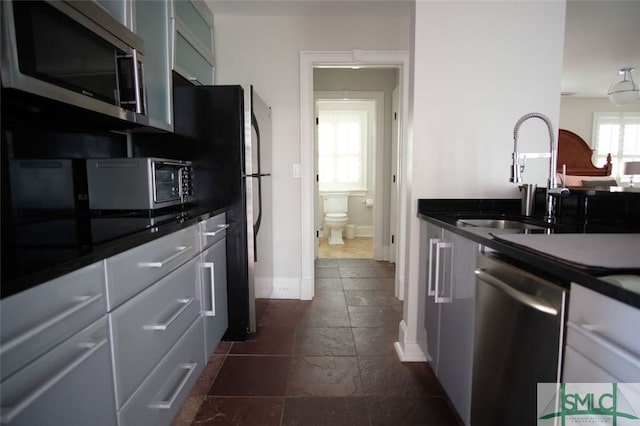 kitchen featuring dark tile flooring, stainless steel appliances, and sink