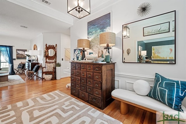 interior space with ornamental molding, wood-type flooring, and a notable chandelier