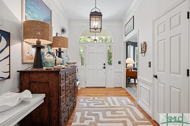 entrance foyer featuring a notable chandelier, light hardwood / wood-style floors, and ornamental molding