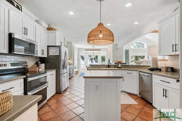 kitchen with stainless steel appliances, tasteful backsplash, white cabinetry, a center island, and light tile floors