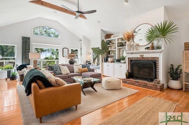 living room with high vaulted ceiling, ceiling fan, light wood-type flooring, and a fireplace