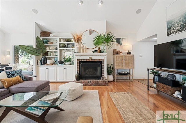 living room with high vaulted ceiling, light hardwood / wood-style floors, and a fireplace