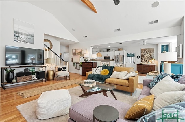 living room featuring light hardwood / wood-style flooring, beam ceiling, and high vaulted ceiling