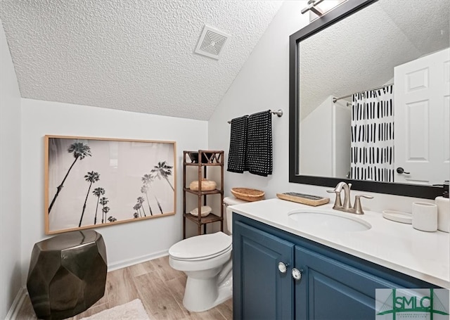 bathroom with vanity, hardwood / wood-style floors, toilet, a textured ceiling, and lofted ceiling