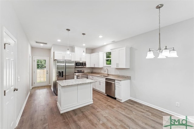 kitchen featuring sink, decorative light fixtures, stainless steel appliances, and a kitchen island