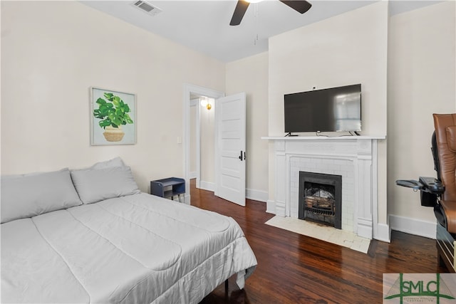 bedroom with ceiling fan, dark hardwood / wood-style floors, and a fireplace