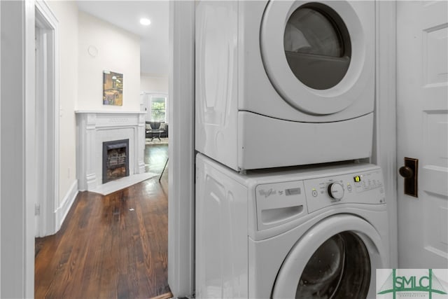 laundry room featuring dark hardwood / wood-style flooring and stacked washer / dryer