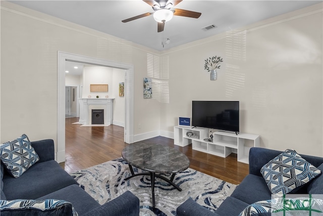 living room featuring ceiling fan, dark wood-type flooring, and crown molding