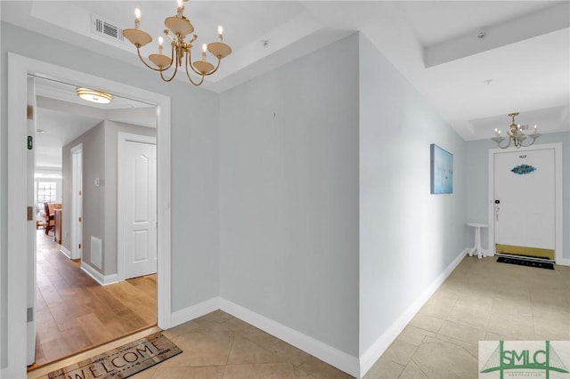 hall with light tile patterned flooring and a notable chandelier