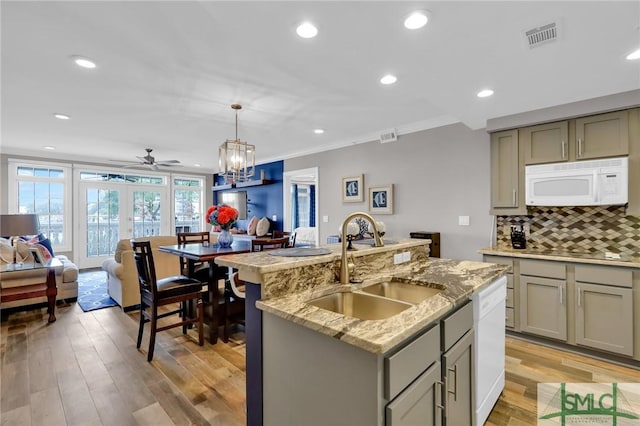 kitchen featuring sink, hanging light fixtures, gray cabinets, an island with sink, and white appliances