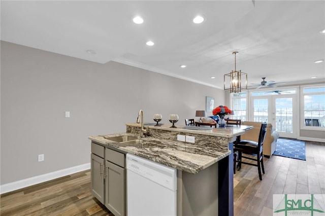 kitchen with wood-type flooring, a kitchen island with sink, sink, and white dishwasher