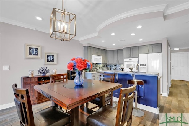 dining room with hardwood / wood-style flooring, ornamental molding, and sink