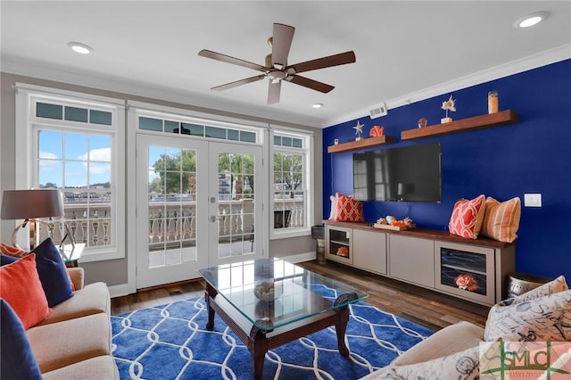 living room with dark wood-type flooring, ceiling fan, crown molding, and french doors