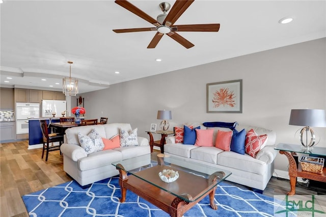 living room featuring ceiling fan, ornamental molding, and light wood-type flooring