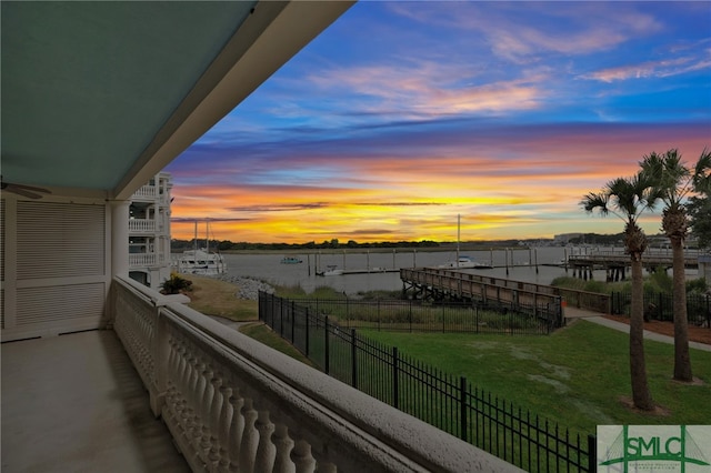 balcony at dusk featuring a water view