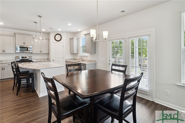 dining room featuring dark wood-type flooring, a notable chandelier, and sink