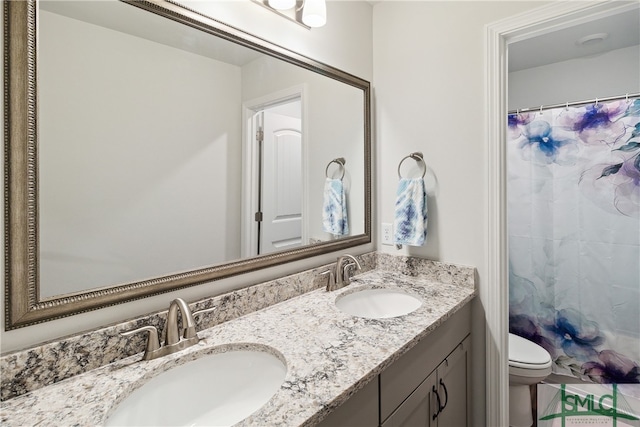 bathroom with toilet and dual vanity