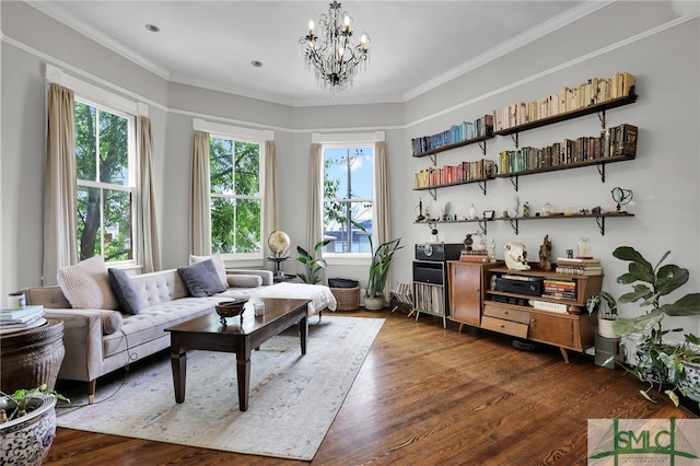 living room featuring a healthy amount of sunlight, wood-type flooring, crown molding, and an inviting chandelier