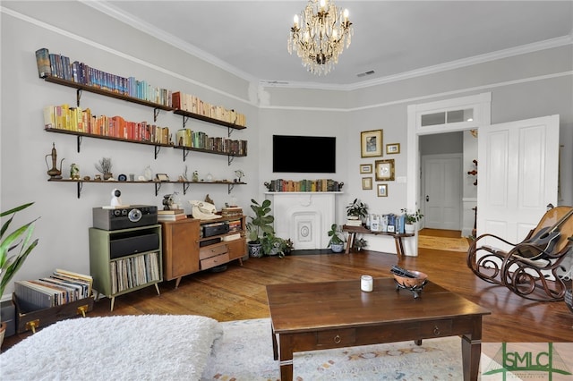 living room with hardwood / wood-style floors, crown molding, and an inviting chandelier