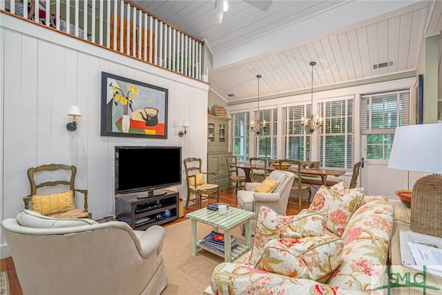 living room with wood-type flooring, lofted ceiling with beams, and a chandelier