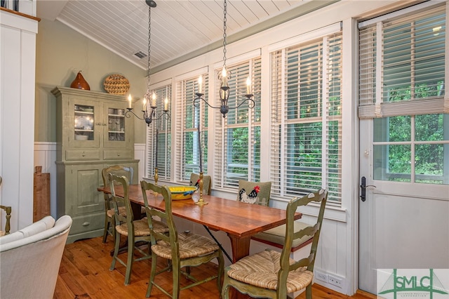 dining space with vaulted ceiling, hardwood / wood-style flooring, and an inviting chandelier