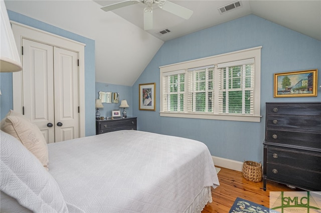 bedroom with a closet, light hardwood / wood-style flooring, ceiling fan, and vaulted ceiling