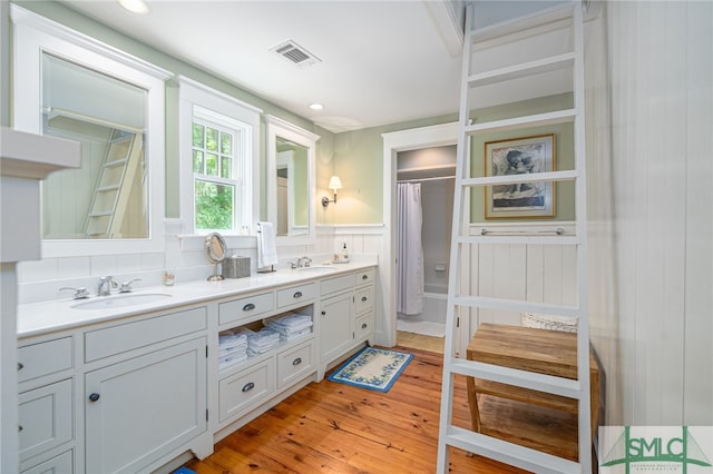 bathroom with hardwood / wood-style flooring, backsplash, and double sink vanity