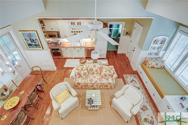 living room with high vaulted ceiling, ceiling fan, and light wood-type flooring