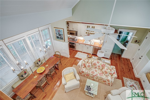 living room featuring light hardwood / wood-style flooring, high vaulted ceiling, and ceiling fan