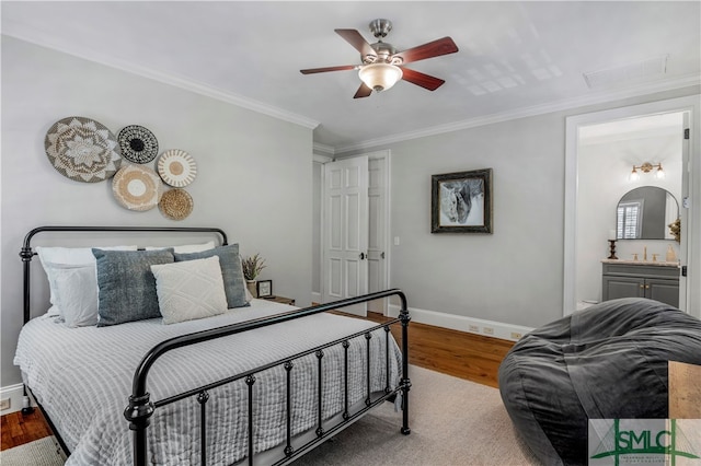 bedroom featuring ensuite bath, hardwood / wood-style floors, ceiling fan, and ornamental molding