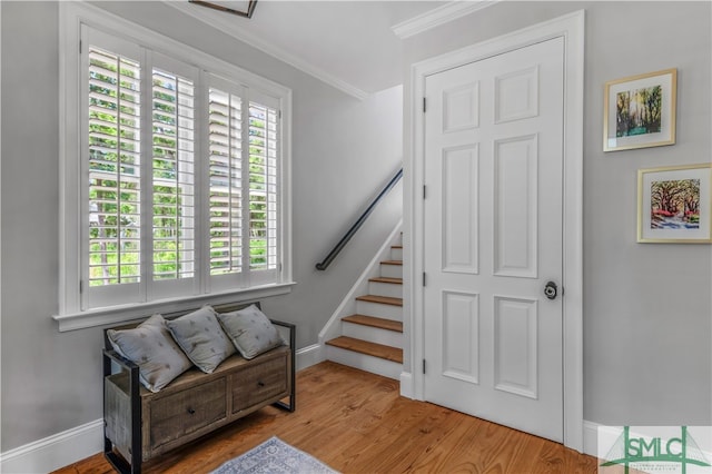 stairs with ornamental molding and light hardwood / wood-style flooring