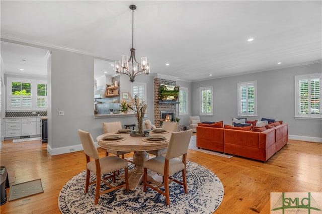 dining room featuring a fireplace, crown molding, and light wood-type flooring