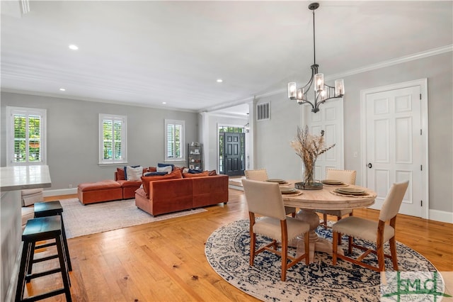 dining space with a notable chandelier, crown molding, and hardwood / wood-style flooring