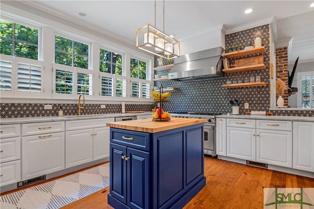 kitchen featuring high end range, backsplash, wall chimney exhaust hood, and white cabinetry