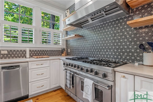 kitchen featuring backsplash, white cabinetry, crown molding, stainless steel appliances, and light hardwood / wood-style flooring