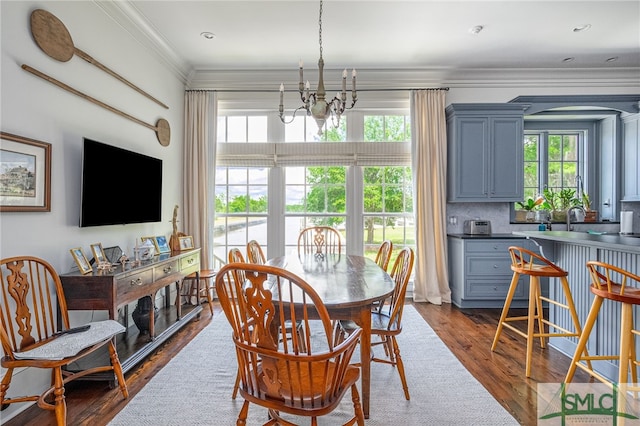 dining room with dark hardwood / wood-style floors, ornamental molding, a healthy amount of sunlight, and an inviting chandelier